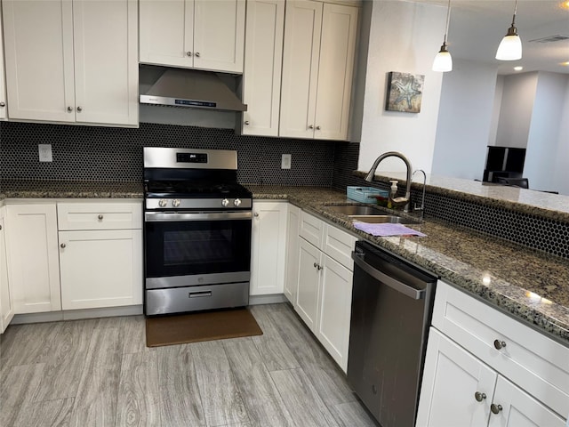 kitchen featuring visible vents, under cabinet range hood, dark stone counters, appliances with stainless steel finishes, and a sink