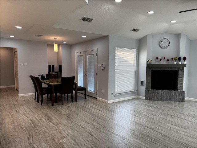 dining space featuring visible vents, baseboards, a brick fireplace, and light wood finished floors