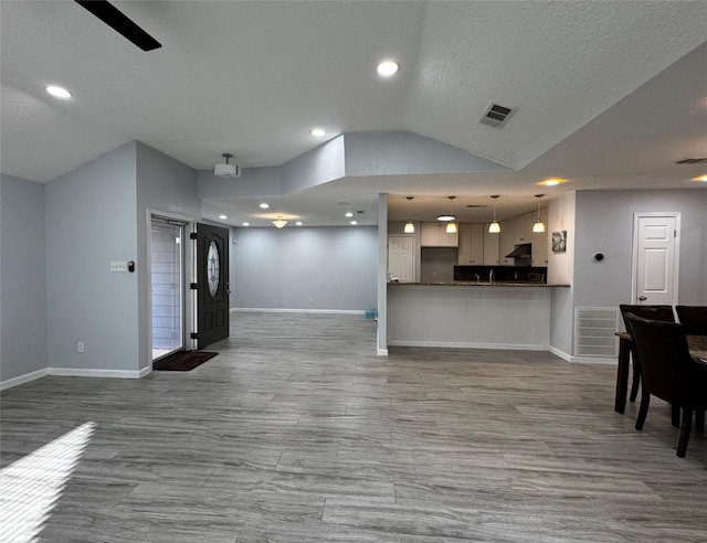 living room with vaulted ceiling, wood finished floors, baseboards, and visible vents