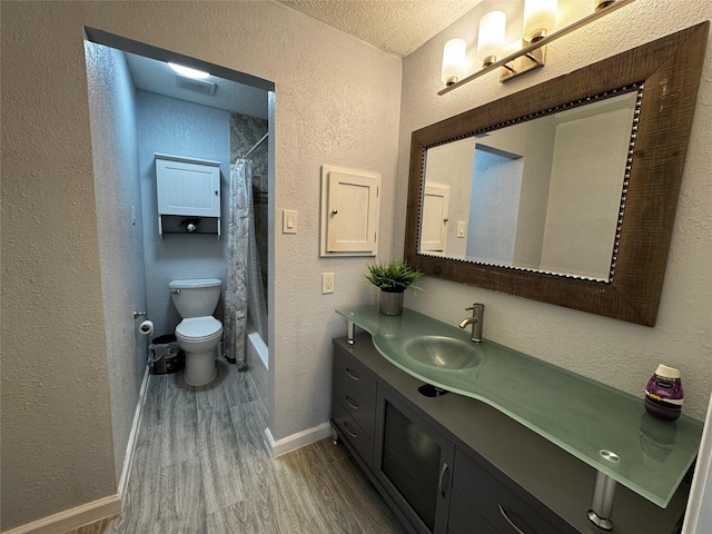 bathroom with toilet, wood finished floors, and a textured wall