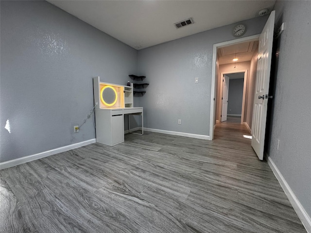 spare room featuring visible vents, baseboards, attic access, and wood finished floors