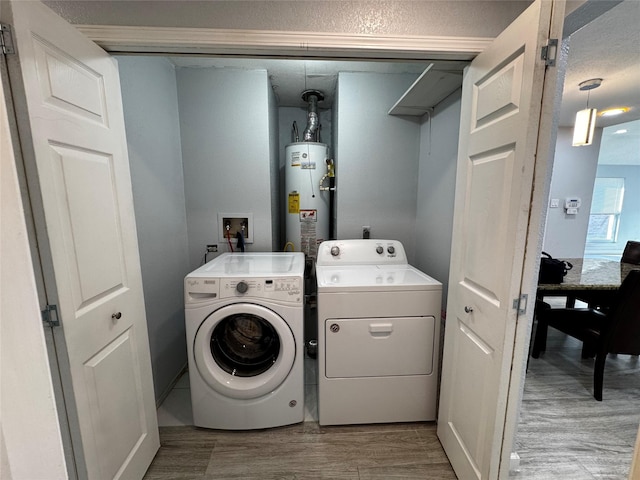 washroom with laundry area, gas water heater, washing machine and dryer, and wood finished floors