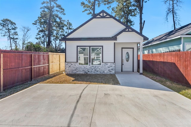 view of front of property with stone siding and a fenced backyard