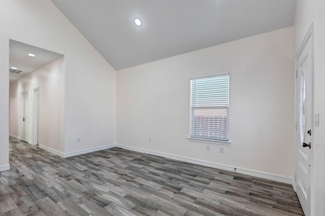 empty room featuring lofted ceiling, recessed lighting, wood finished floors, and baseboards