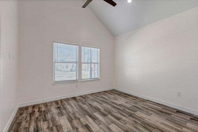 empty room with high vaulted ceiling, wood finished floors, baseboards, and ceiling fan