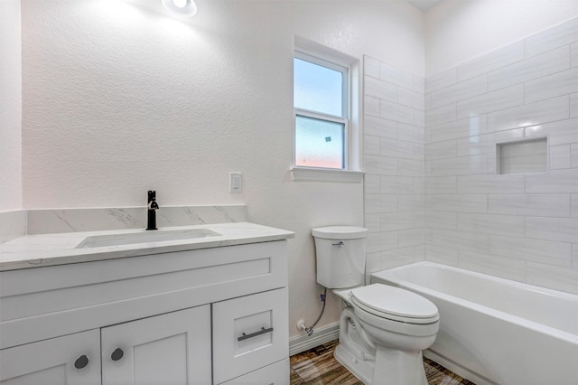 full bath with baseboards, toilet, wood finished floors, a textured wall, and vanity