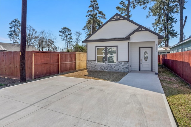 view of front of property featuring stone siding and a fenced backyard