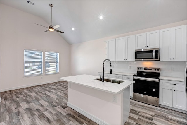 kitchen featuring visible vents, light wood-type flooring, decorative backsplash, stainless steel appliances, and a sink