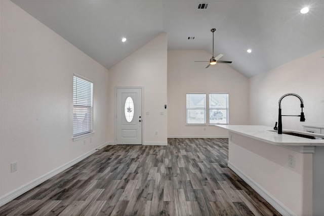 entryway with visible vents, baseboards, ceiling fan, wood finished floors, and high vaulted ceiling