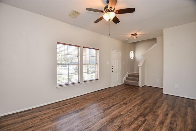 unfurnished living room with visible vents, dark wood-type flooring, baseboards, ceiling fan, and stairs