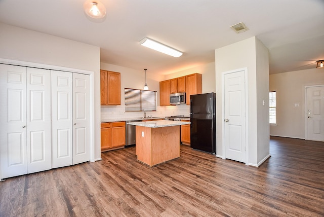 kitchen featuring visible vents, tasteful backsplash, a kitchen island, dark wood-style floors, and stainless steel appliances