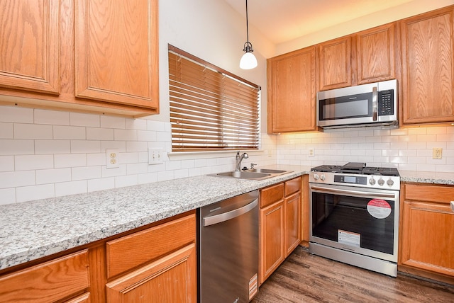 kitchen with backsplash, decorative light fixtures, wood finished floors, stainless steel appliances, and a sink