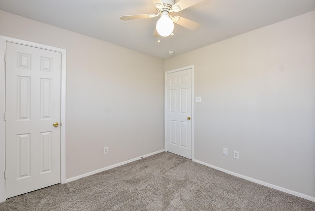 carpeted spare room featuring baseboards and ceiling fan