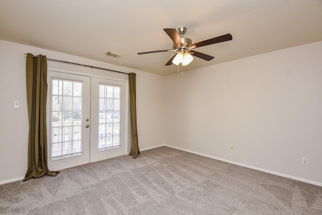 empty room featuring a ceiling fan, french doors, visible vents, and light carpet