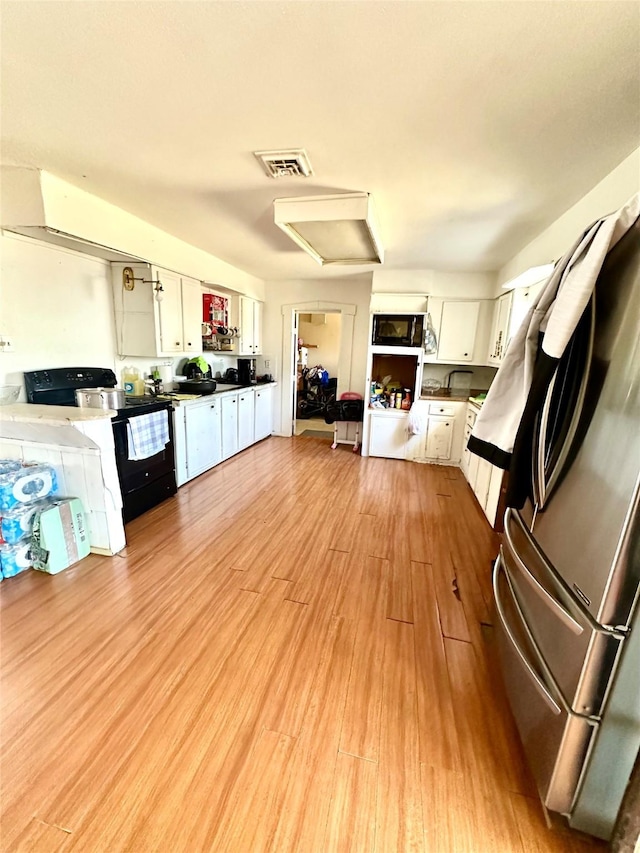 kitchen featuring electric range, visible vents, freestanding refrigerator, white cabinets, and light wood finished floors