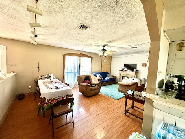 interior space with visible vents, a ceiling fan, a textured ceiling, wood finished floors, and baseboards