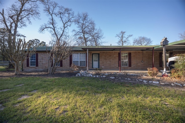 view of front facade with an attached carport, brick siding, and a front yard