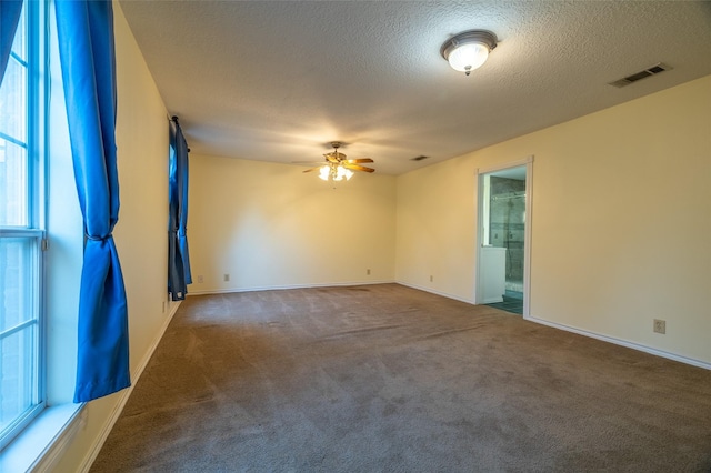 carpeted empty room featuring baseboards, a ceiling fan, visible vents, and a textured ceiling