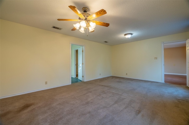 carpeted spare room featuring visible vents, baseboards, a textured ceiling, and a ceiling fan