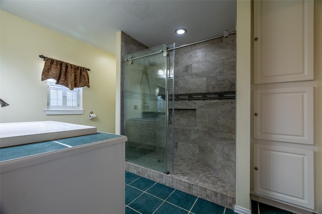 full bathroom with a sink, a shower stall, tile patterned floors, and a textured ceiling