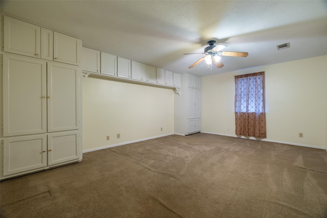 carpeted spare room featuring visible vents, a ceiling fan, baseboards, and a textured ceiling