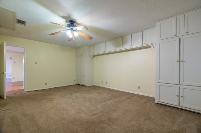 spare room featuring visible vents, baseboards, ceiling fan, light carpet, and a textured ceiling