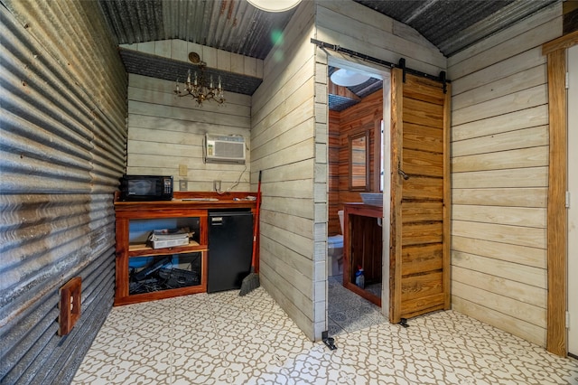 interior space with refrigerator, a wall unit AC, a barn door, black microwave, and vaulted ceiling