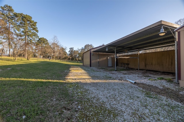 view of yard featuring a carport, an outdoor structure, driveway, and a pole building