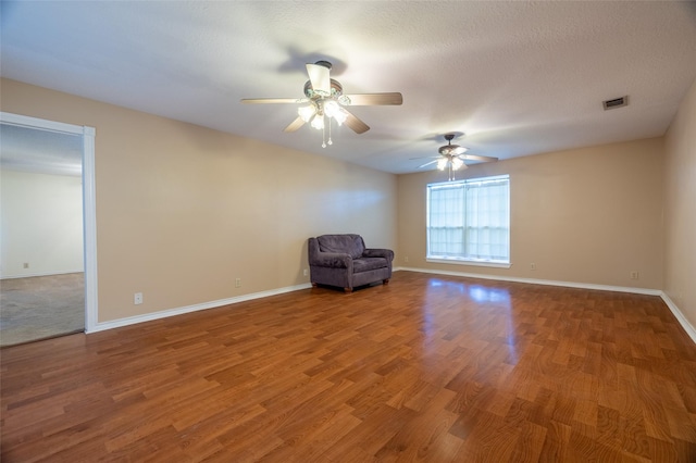 unfurnished room featuring visible vents, baseboards, wood finished floors, and a ceiling fan