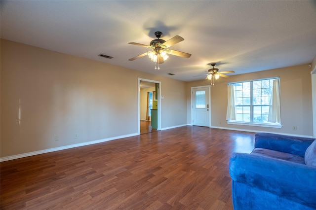 unfurnished living room with baseboards, visible vents, dark wood-style flooring, and ceiling fan