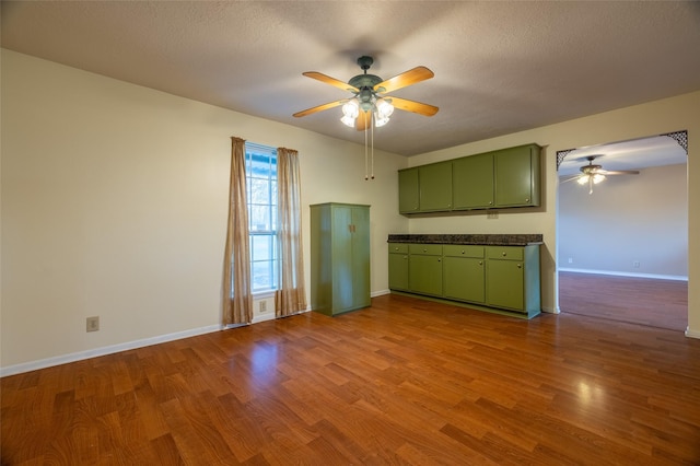 kitchen featuring green cabinets, dark countertops, wood finished floors, and ceiling fan