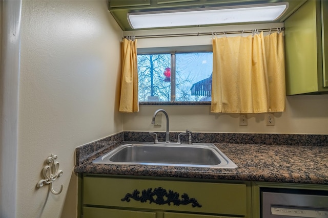 kitchen with a sink, dark countertops, dishwasher, and green cabinets