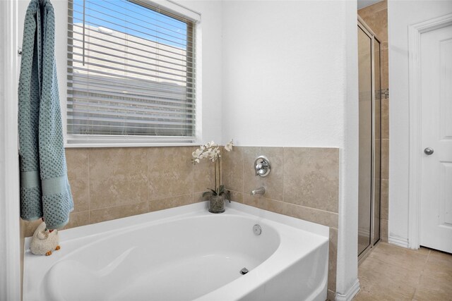 bathroom with a shower stall, a bath, and tile patterned floors