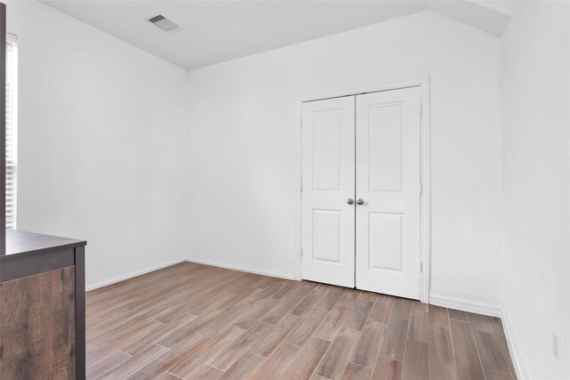 empty room featuring wood finish floors, visible vents, and baseboards