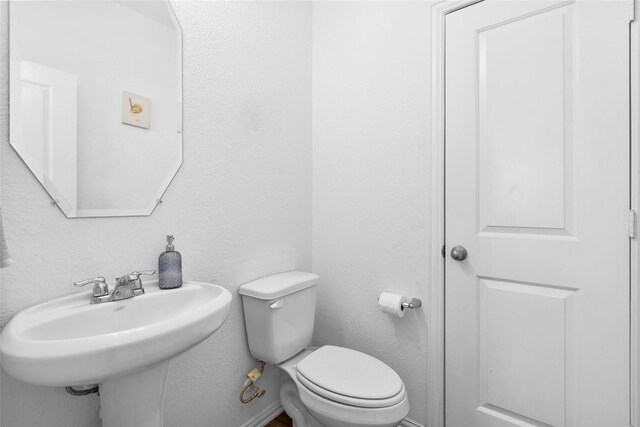 bathroom featuring toilet, baseboards, and a sink