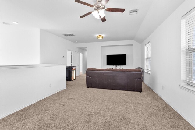 carpeted living area with visible vents, plenty of natural light, and a ceiling fan