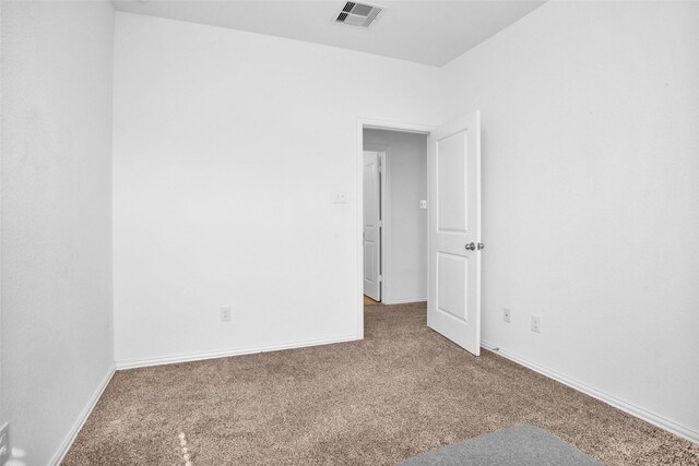 carpeted spare room with visible vents and baseboards