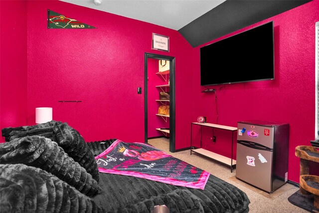 bedroom featuring lofted ceiling and freestanding refrigerator