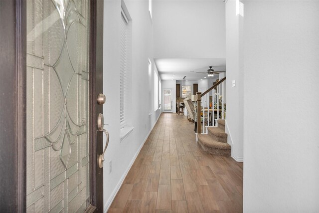 foyer with stairway, baseboards, ceiling fan, and wood finished floors