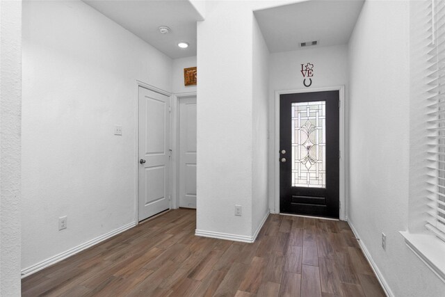 foyer featuring visible vents, baseboards, and wood finished floors