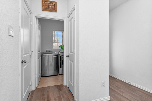 corridor with wood finished floors and washing machine and dryer