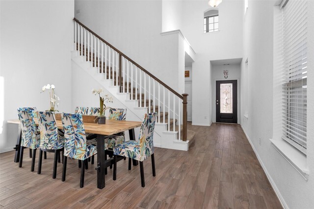 dining space with stairs, wood finished floors, baseboards, and a healthy amount of sunlight