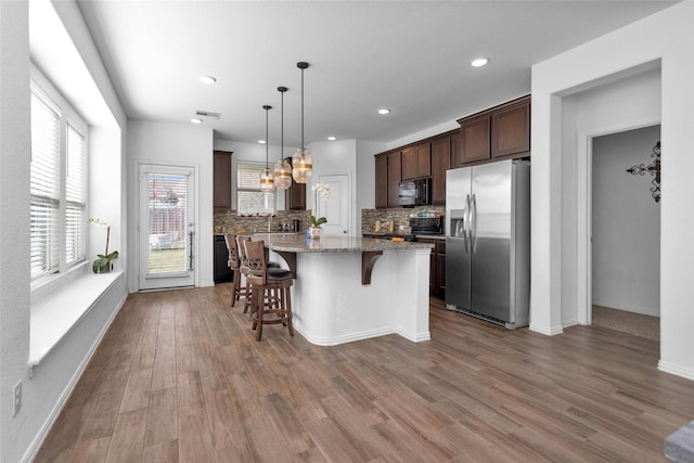 118 Emory Birch Dr, Montgomery, TX 77316 - kitchen with a breakfast bar area, a center island, backsplash, and black appliances