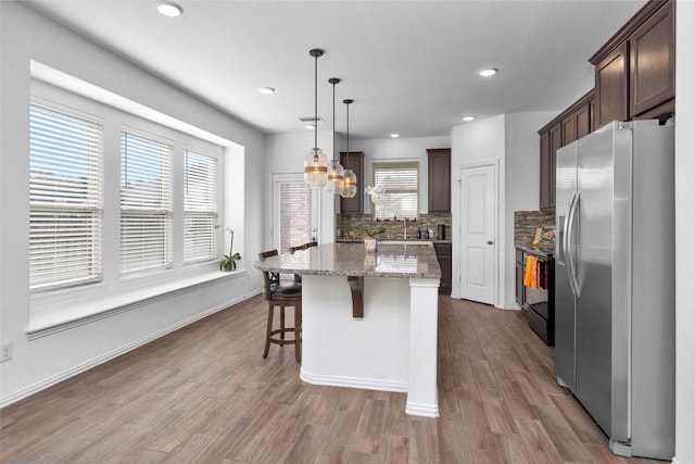 118 Emory Birch Dr, Montgomery, TX 77316 - kitchen with dark wood-style flooring, tasteful backsplash, dark brown cabinetry, stainless steel fridge with ice dispenser, and a kitchen island