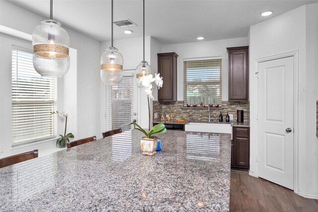 kitchen with visible vents, dark wood-style flooring, a sink, pendant lighting, and backsplash