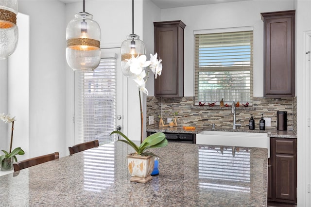 118 Emory Birch Dr, Montgomery, TX 77316 - kitchen featuring a sink, decorative light fixtures, dark stone counters, dark brown cabinetry, and tasteful backsplash