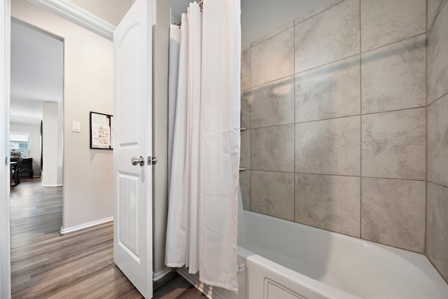 bathroom with shower / tub combo, wood finished floors, and baseboards