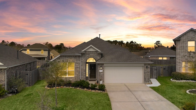 view of front of house featuring brick siding, fence, concrete driveway, roof with shingles, and a lawn