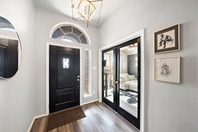 foyer entrance featuring wood finished floors, baseboards, and french doors