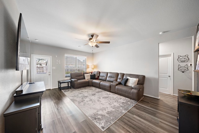 living room featuring baseboards, ceiling fan, and dark wood finished floors